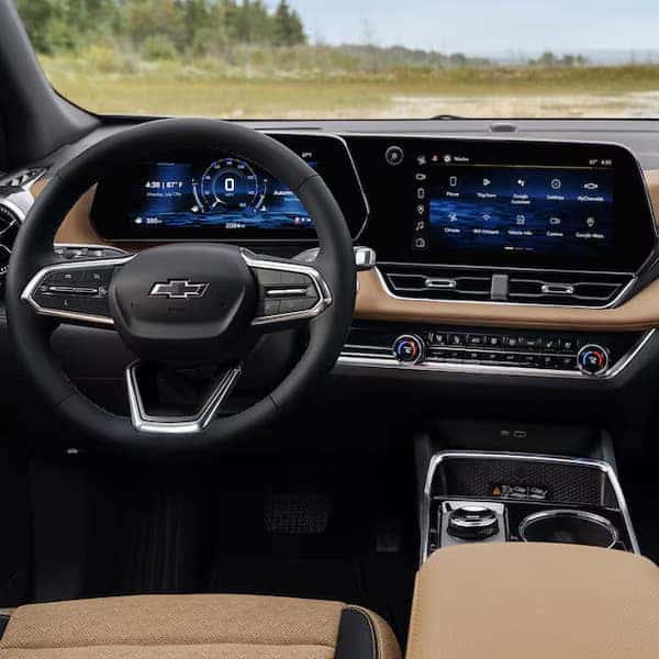 The image shows a modern car interior featuring a steering wheel with multiple controls and a large, vertical touchscreen in the center console displaying various apps and settings. The dashboard is sleek and technologically advanced.