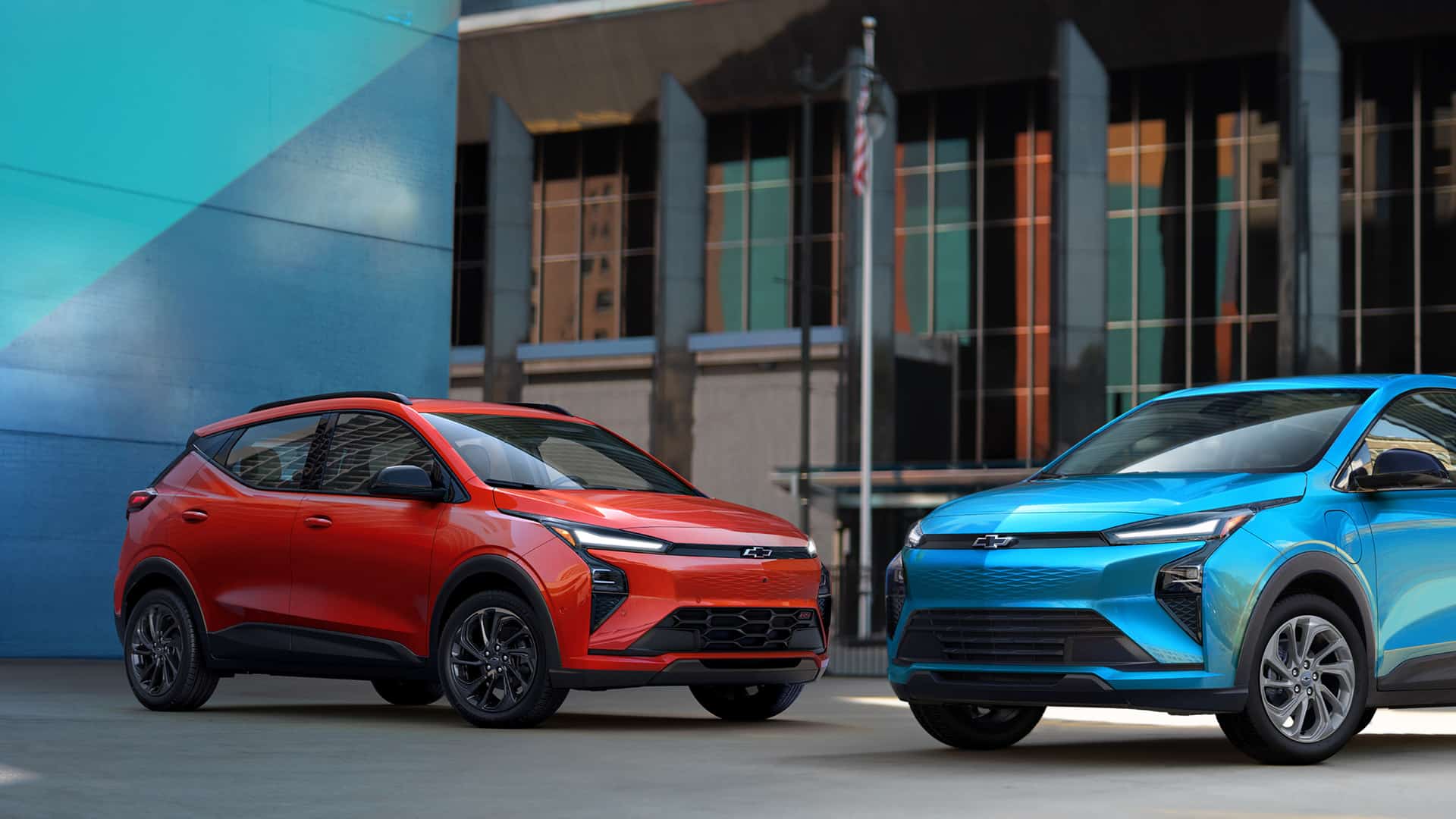 Red and blue electric SUVs parked in urban setting, showcasing modern design and sleek lines.