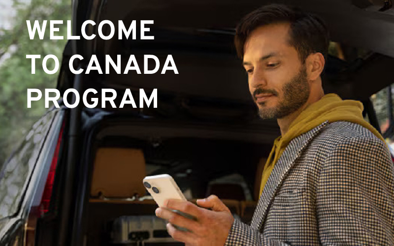 Man checking phone by car trunk, text reads "Welcome to Canada Program."