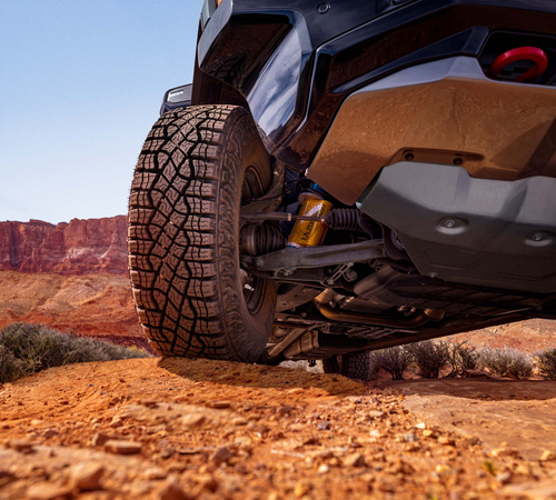 Off-road vehicle navigating rocky desert terrain, highlighting tire tread and suspension.