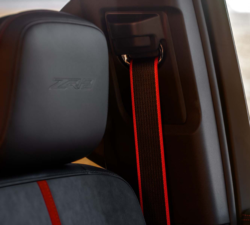 Car interior featuring a black and red seatbelt with a headrest embroidered with "ZR2."