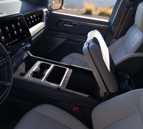 Luxurious car interior with cream leather seats, modern touchscreen display, and open center console.