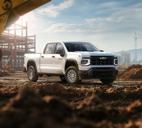 White pickup truck on a construction site with building framework and machinery in the background.